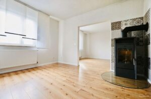 Heller Wohn-/Essbereich mit Kamin (mittels KI entmöbliert).